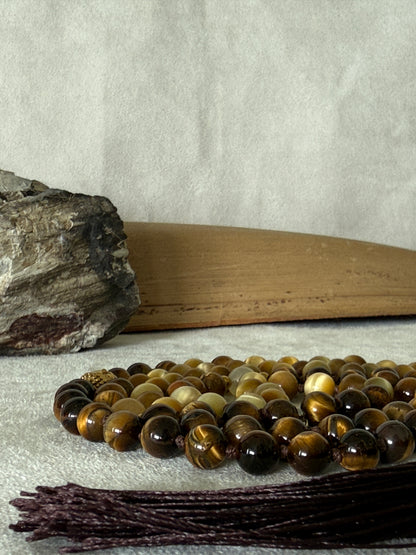 Handmade 108-bead mala necklace with tiger's eye and yellow jade, featuring a Lotus and Buddha charm pendant, designed for grounding, clarity, and centering.