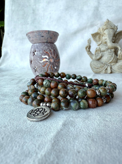 Full view of Rhyolite jasper mala bracelet with lotus charm, green and brown forest rhyolite for purity and transformation.