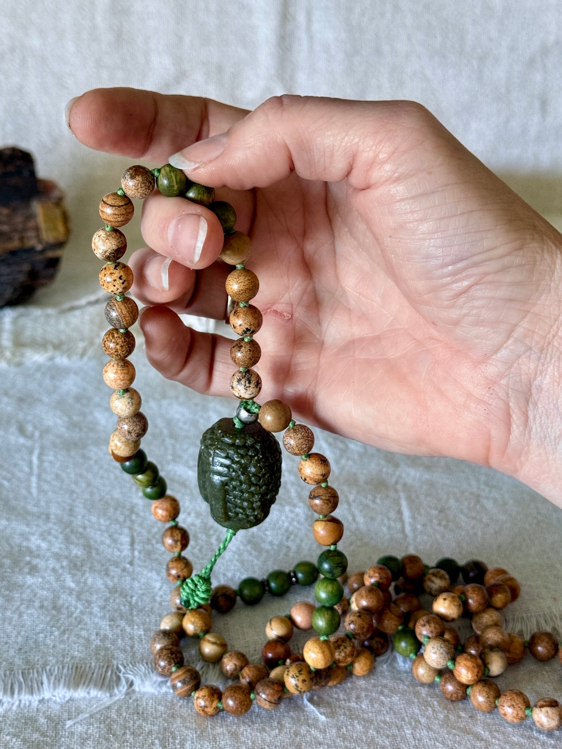 Hand-carved Jade Buddha pendant used as the meru bead on a sandalwood and sand jasper mala necklace, Mala beads for meditation