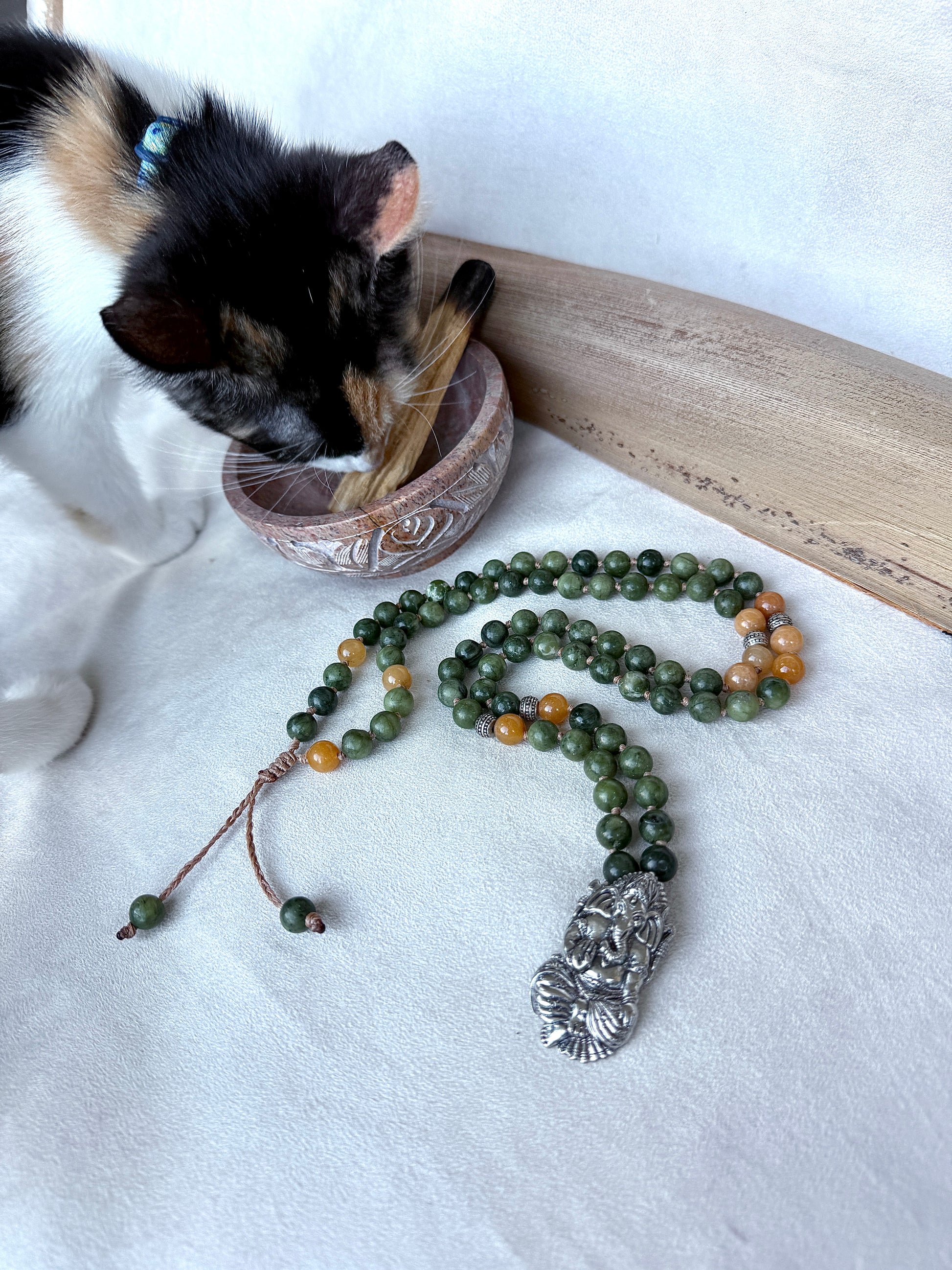 Meditation setup with jade mala resting on selenite bowl for energetic cleansing with cat