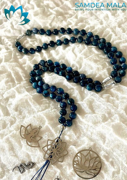 Solid kyanite mala laid out with a selection of interchangeable pendant charms - lotus, tree of life and tassel - to choose from for a custom mala