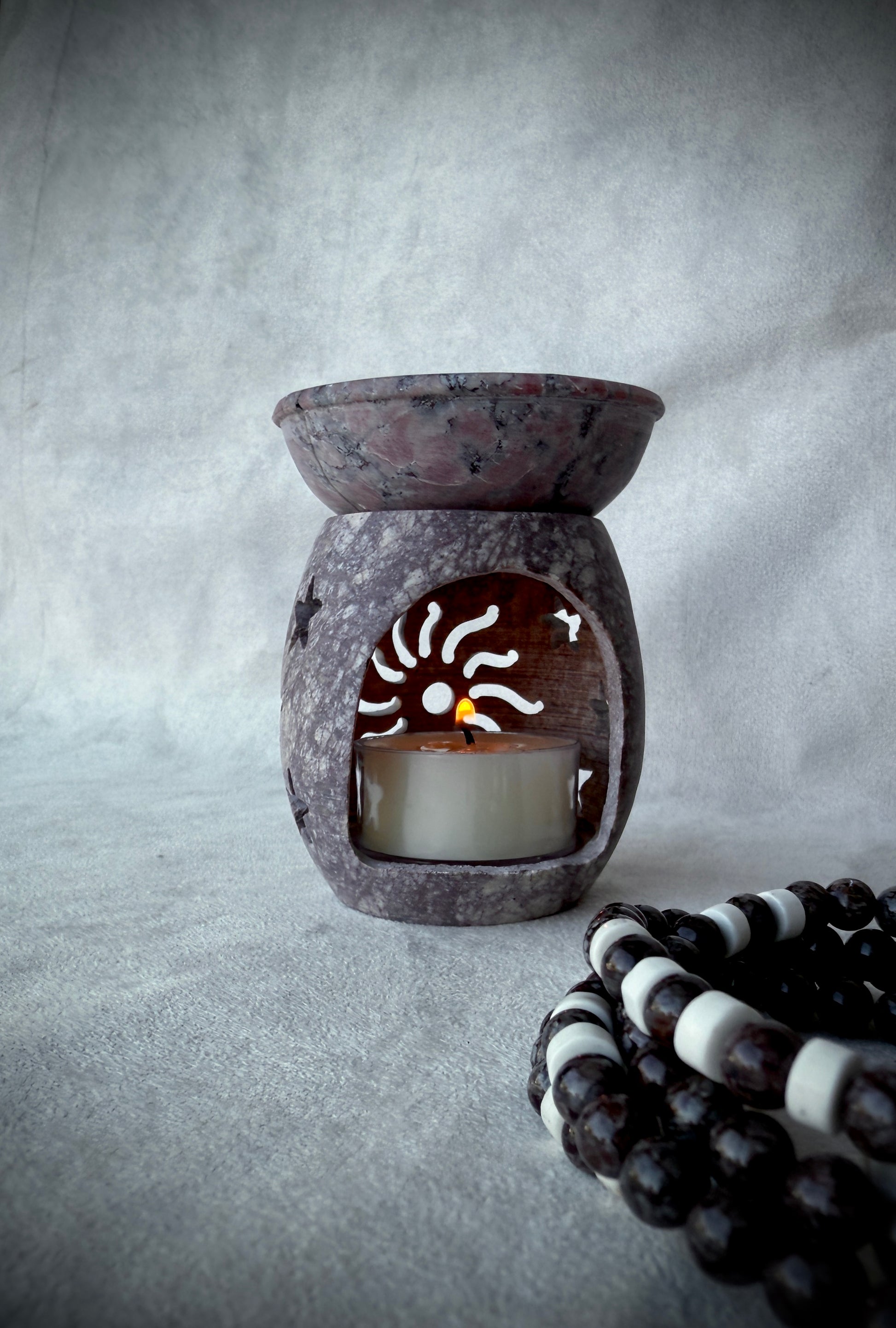 Meditation corner styled with mala beads and soapstone incense burner, serene home altar tealight