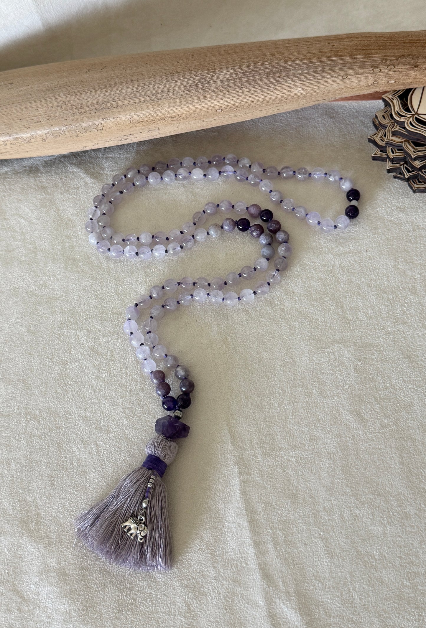 Full view of Purple lavender mala necklace for meditation. Handmade 108 bead mala in natural gemstone 8 mm lavender jade, lepidolite and amethyst with cotton tassel and small elephant charm.