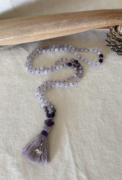 Full view of Purple lavender mala necklace for meditation. Handmade 108 bead mala in natural gemstone 8 mm lavender jade, lepidolite and amethyst with cotton tassel and small elephant charm.