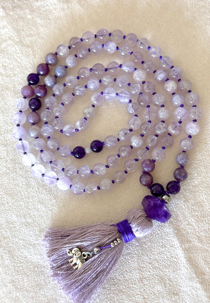 Lavender jade, lepidolite and amethyst 108 bead mala coiled flat, showing the full strand with the amethyst meru bead and silver elephant charm on the tassel