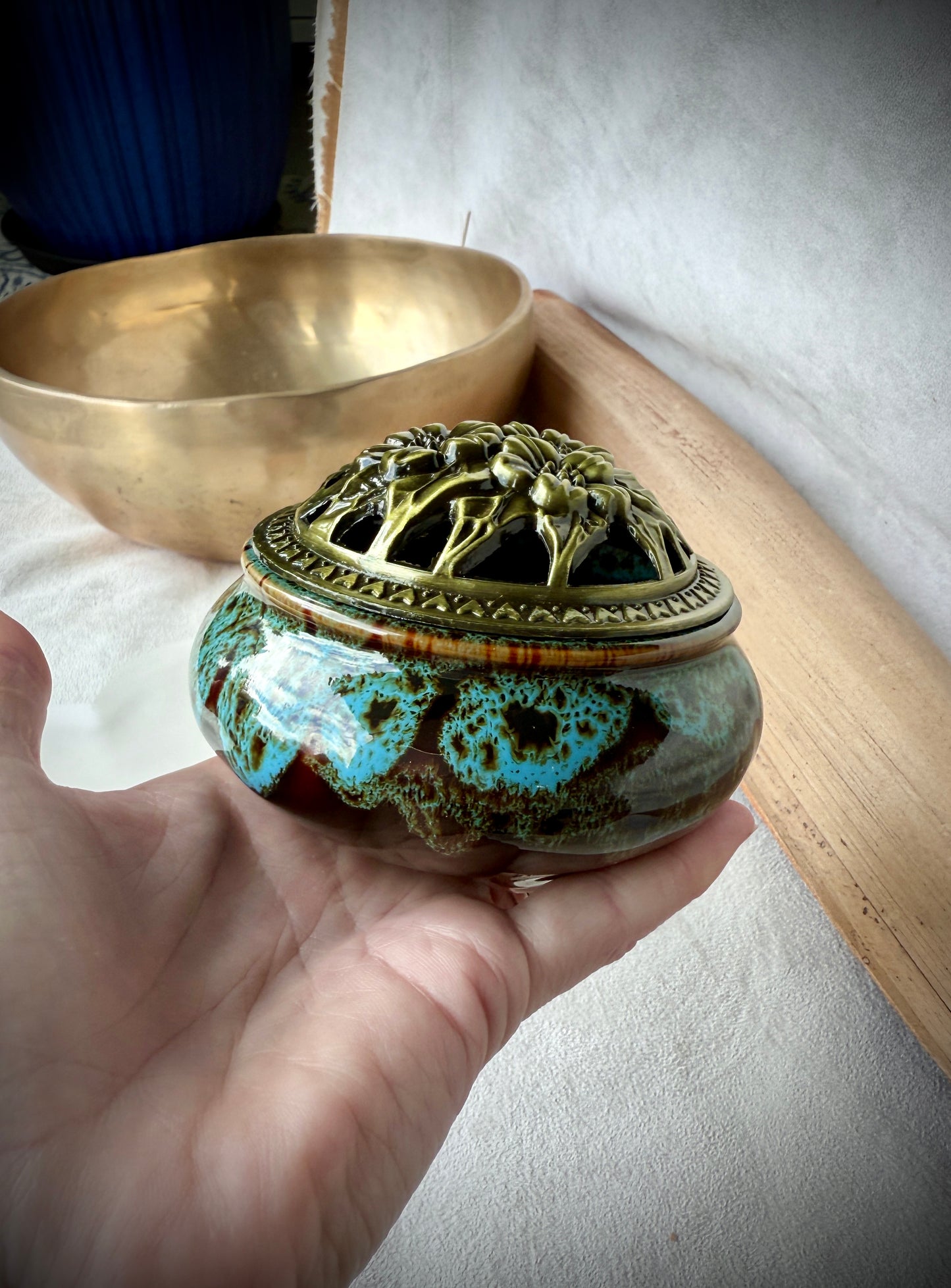 Small round ceramic bowl in deep blue glaze with a removable golden metallic lid, artisanal tabletop decor - Samdea Mala on a hand