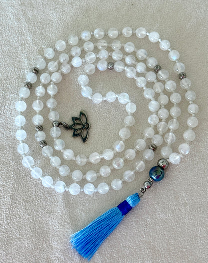 Handmade Rainbow Moonstone mala for meditation with 108 prayer beads, 6 mm natural gemstone beads, Aqua Aura Quartz meru, stainless steel details, small lotus charm, and tassel, created for meditation, breathwork, mantra repetition, mindfulness, and intentional practice. Samdea Mala