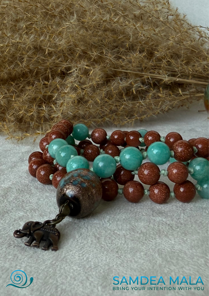 Close-up of Samdea short mala with sunstone and amazonite beads, ceramic meru and elephant charm, Spiritual necklace