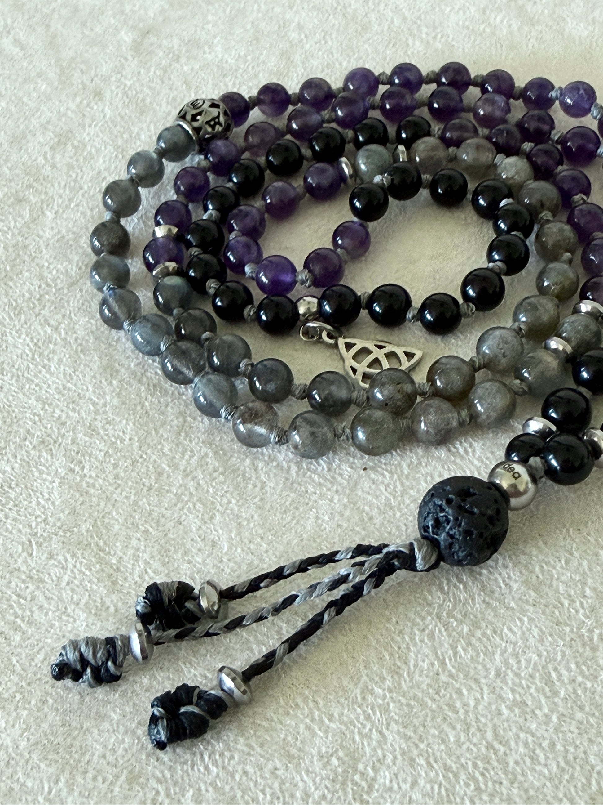 close up of Shadow Work Mini Mala with 108 natural 6mm gemstone beads in obsidian, amethyst, and labradorite, finished with a black tassel and silver Triquetra charm by Samdea