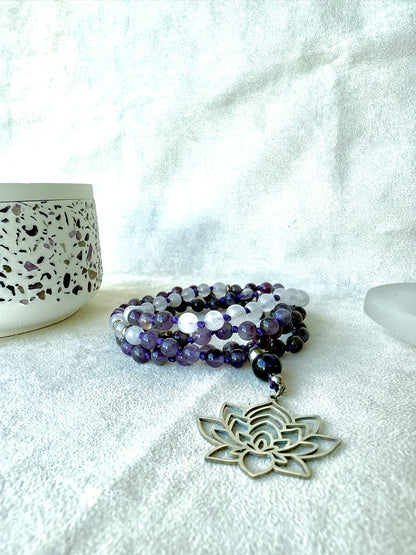 White jade and amethyst mala beads coiled on altar, spiritual jewelry for mindfulness