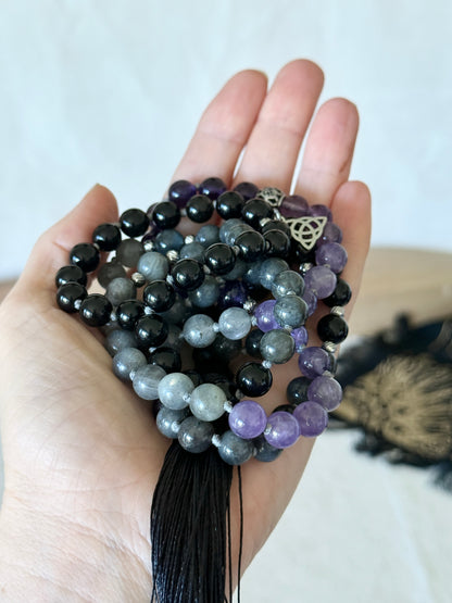a hand holding the Shadow Work Mala beads in obsidian, amethyst and dark labradorite
