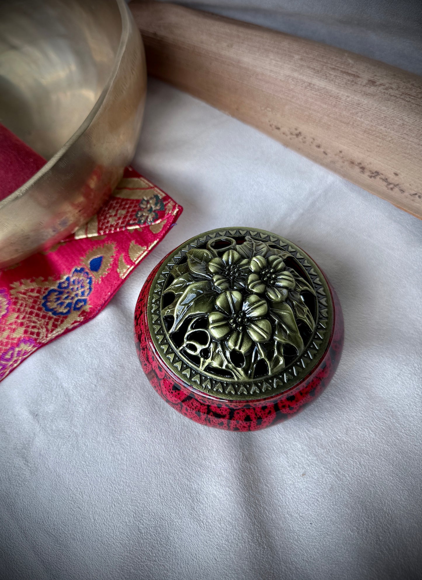 Small round ceramic bowl in deep red glaze with a removable golden metallic lid, artisanal tabletop decor.
