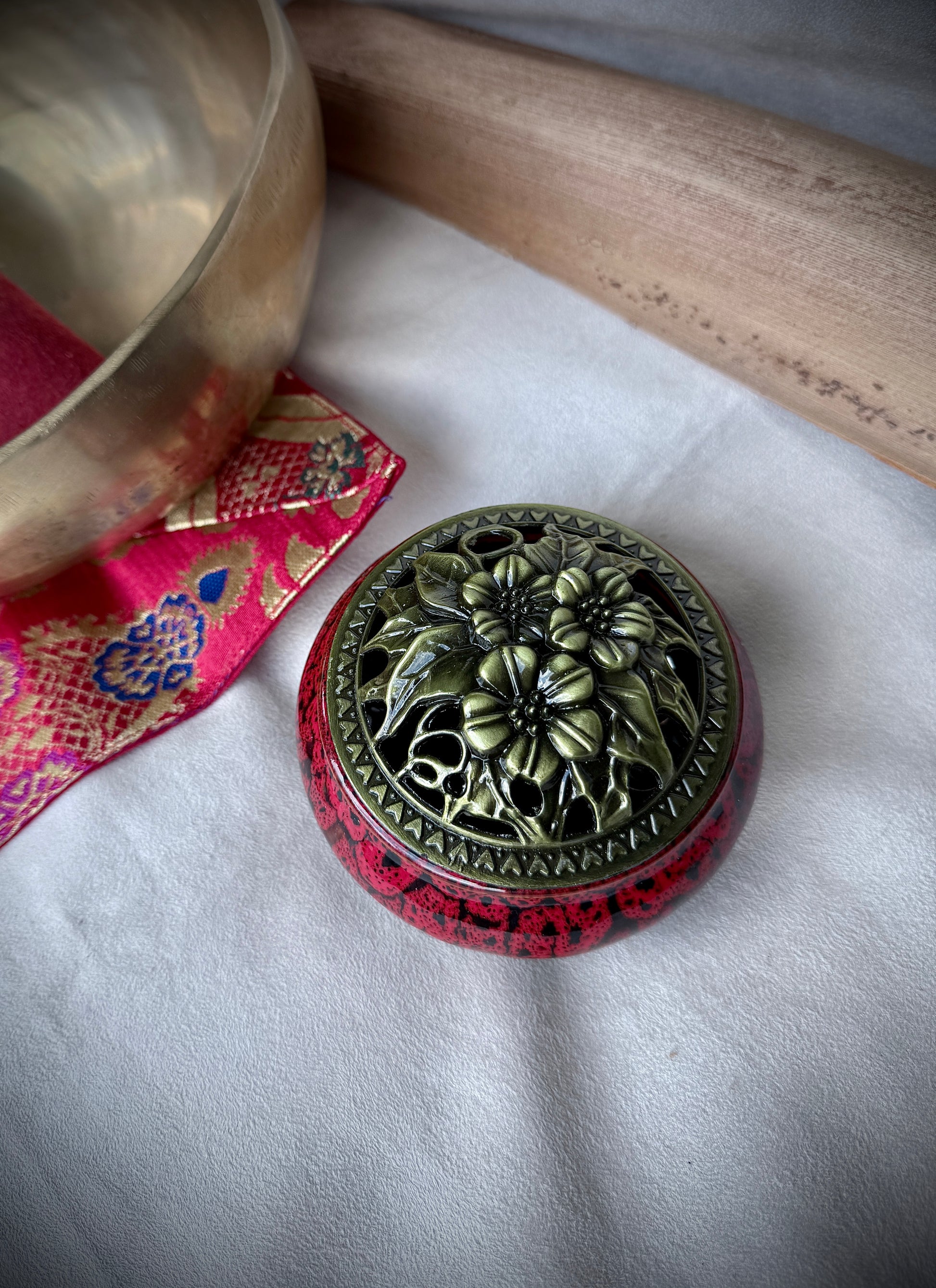 Small round ceramic bowl in deep red glaze with a removable golden metallic lid, artisanal tabletop decor.