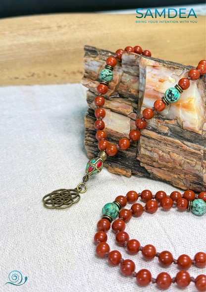 detail fo seeds of life pendant on a mala beads with Red Jasper and African Turquoise, hand-knotted with 108 beads for meditation and personal growth. Earthy red and green tones, spiritual jewelry for grounding, strength, and transformation.