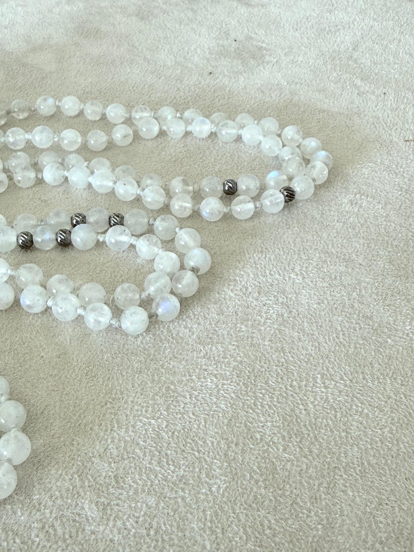 Detail of a  Handmade Rainbow Moonstone mala for meditation with 108 prayer beads, 6 mm natural gemstone beads, Aqua Aura Quartz meru, stainless steel details, small lotus charm, and tassel, created for meditation, breathwork, mantra repetition, mindfulness, and intentional practice. Samdea Mala