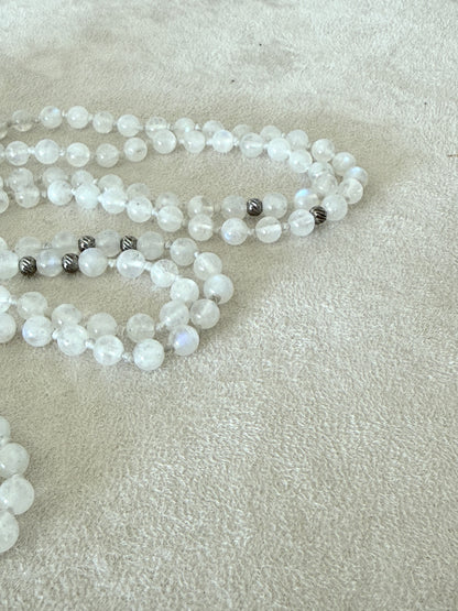 Detail of a  Handmade Rainbow Moonstone mala for meditation with 108 prayer beads, 6 mm natural gemstone beads, Aqua Aura Quartz meru, stainless steel details, small lotus charm, and tassel, created for meditation, breathwork, mantra repetition, mindfulness, and intentional practice. Samdea Mala