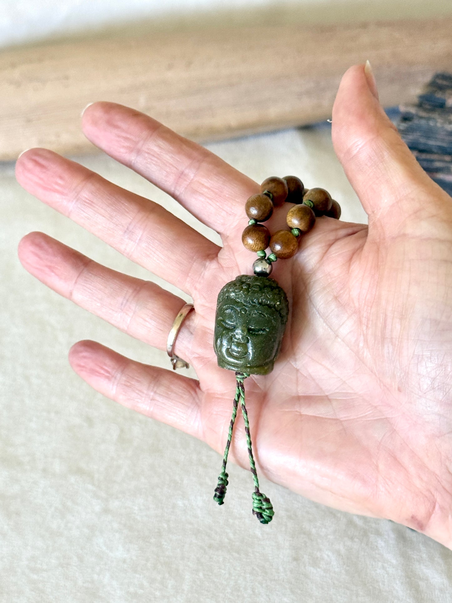 Close-up of the hand-carved jade Buddha pendant on the sandalwood and Indian agate mala, front view