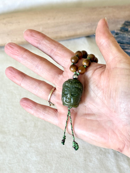 Close-up of the hand-carved jade Buddha pendant on the sandalwood and Indian agate mala, front view