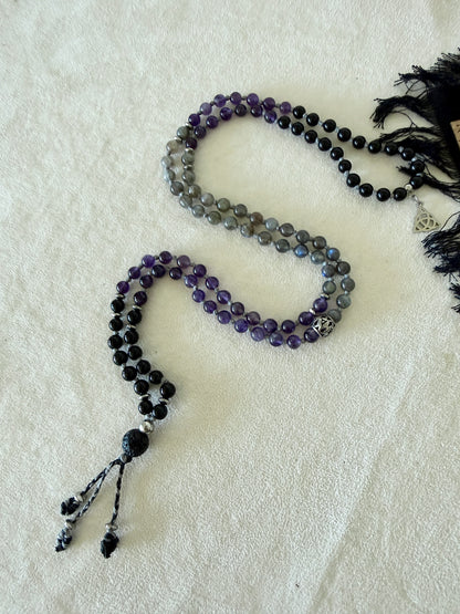 Shadow Work Mini Mala coiled to show the full 6mm bead pattern in obsidian, amethyst, and labradorite, with Triquetra charm and lava stone meru.