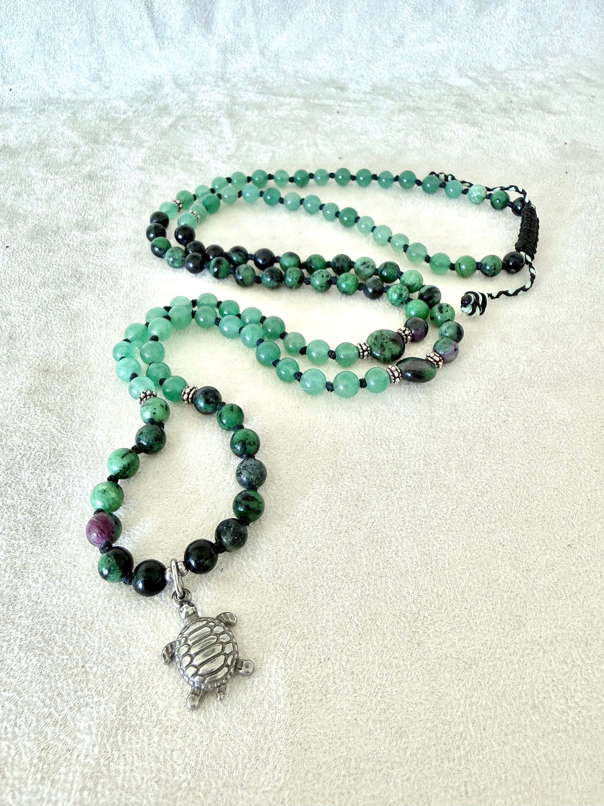 full view of green mala bracelet with 100% natural gemstones, stainless steel turtle charm, adjustable macramé closure, and 108 bead mala necklace design for yoga, meditation, gentle growth, protection, and spiritual transformation. 