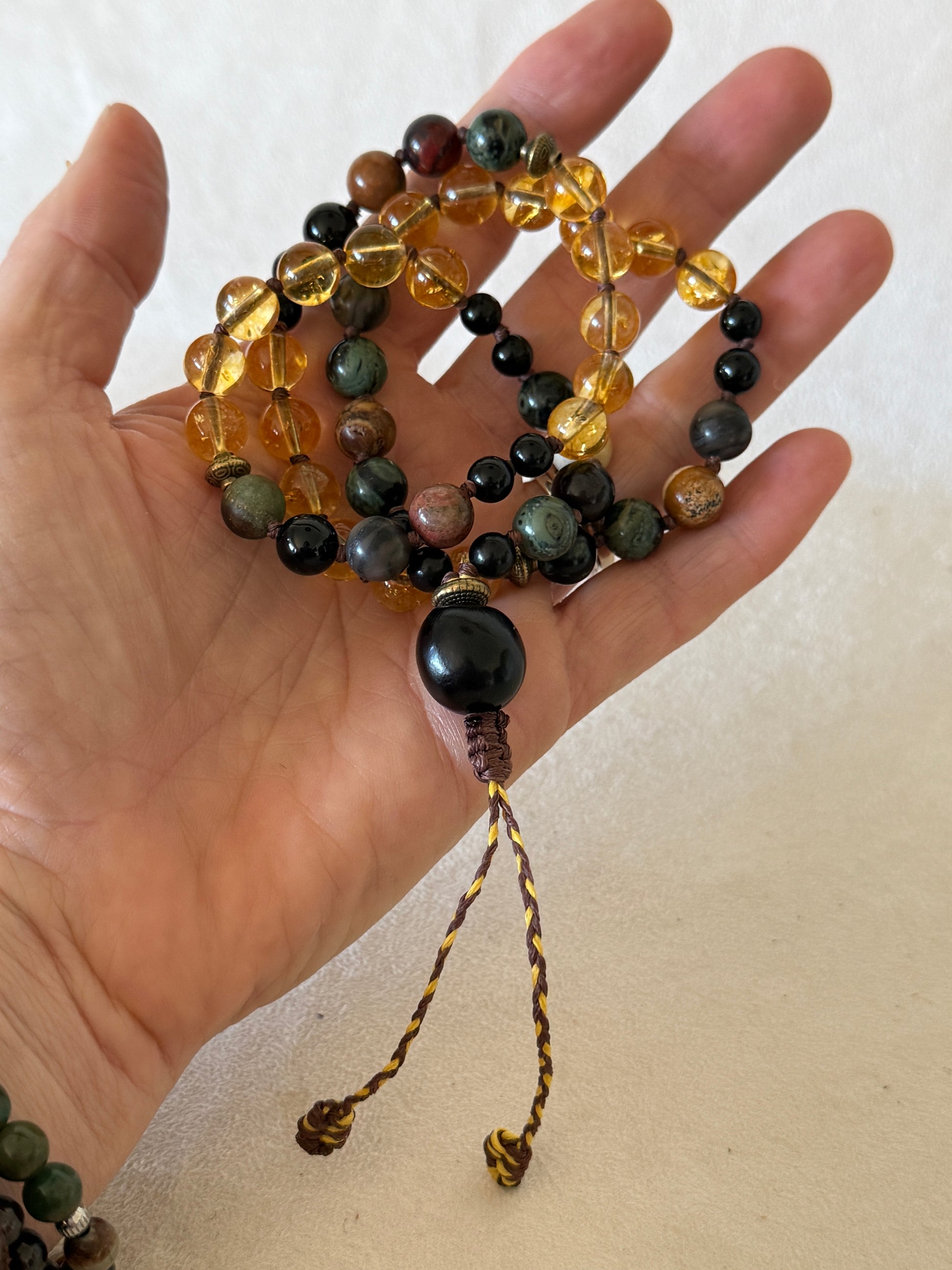 hand holding  a Breathwork Handmade Pause Breathing Mala with natural gemstone beads, designed to guide a 4–2–6 breathing practice through touch without the need to count. Soapberry meru