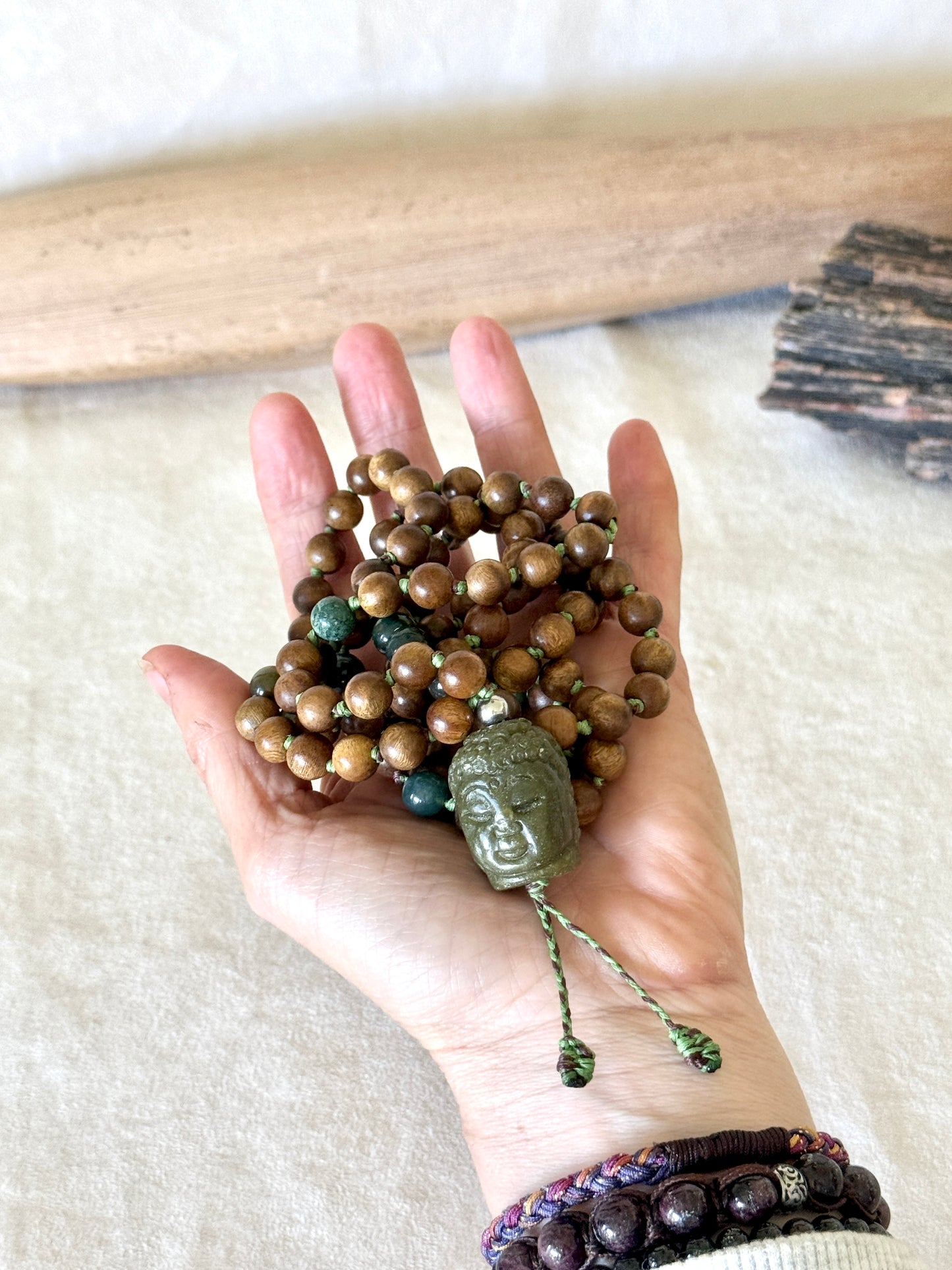 Natural sandalwood and Indian agate prayer beads mala draped over a hand