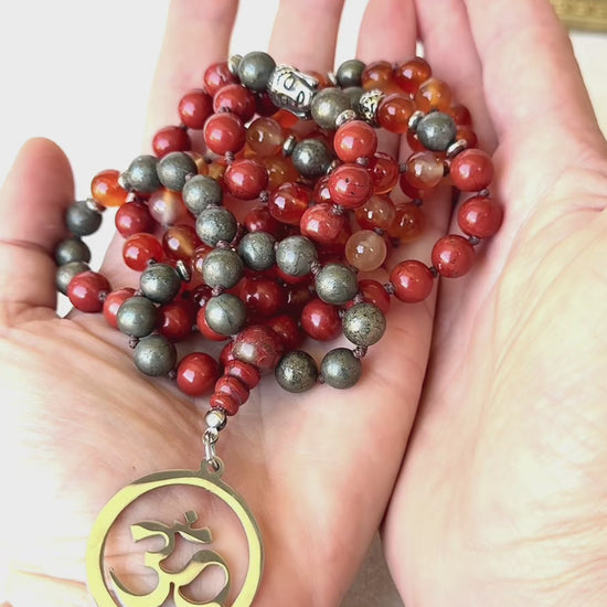 Video preview of Grounding Mala Necklace – Red Jasper, Carnelian, Pyrite | 108 Beads for Courage, Vitality & Inner Strength | Root Chakra Mala - zodiac sign Aries, detail of OM pendant