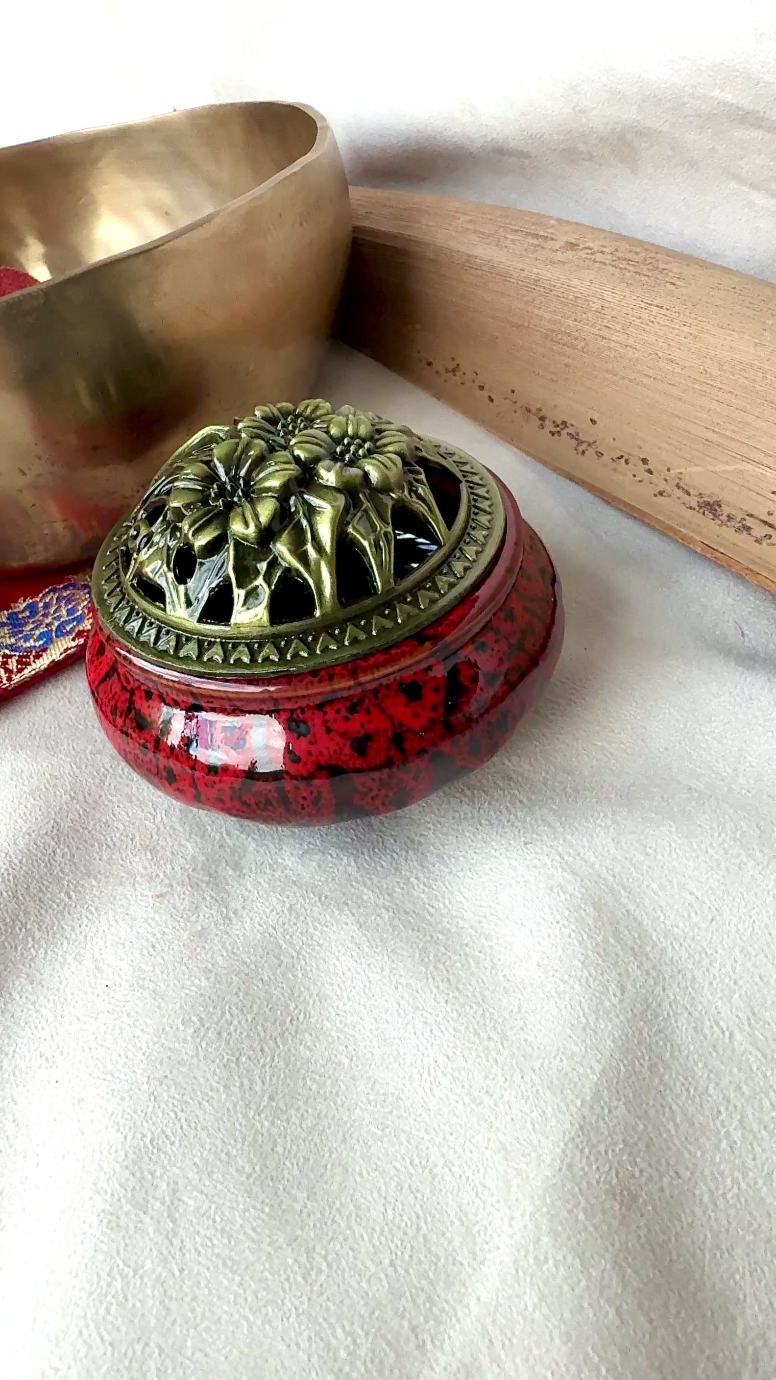 video of Small round ceramic bowl in deep red glaze with a removable golden metallic lid, artisanal tabletop decor.