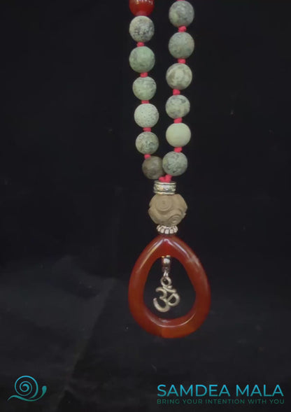 Video of mala pendant in red agate with om charm. Wood meru for good vibrations.