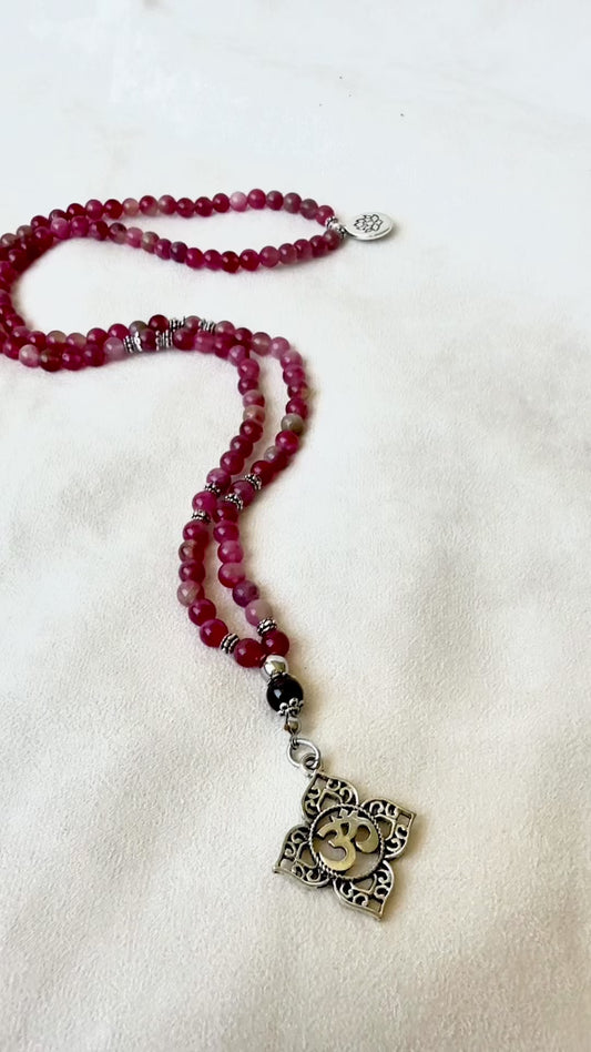 Video preview of Mala necklace in watermelon tourmaline for heart chakra healing. Heart chakra mala beads necklace with OM and lotus charm. Mala for Meditation for women with watermelon tourmaline and garnet for heart protection and clarity with Anahata chakra pendant.