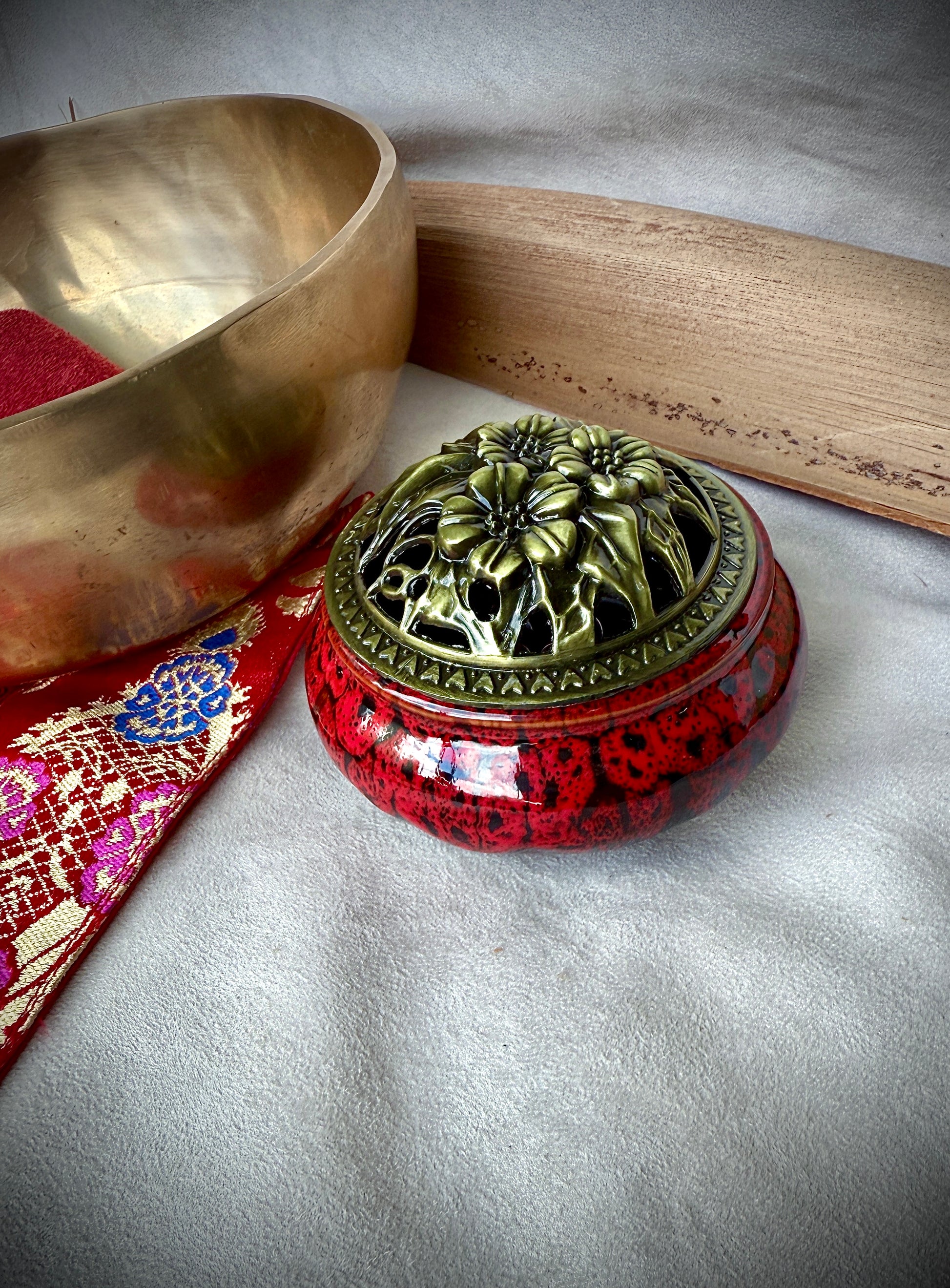 Small round ceramic bowl in deep red glaze with a removable golden metallic lid, artisanal tabletop decor.