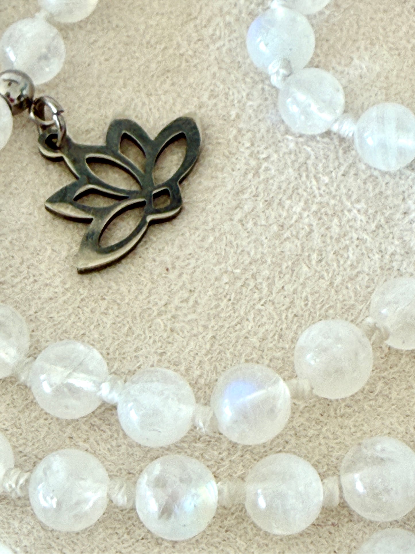 small lotus charm, detail on a Hand-knotted Rainbow Moonstone mala necklace with 108 prayer beads, 6 mm natural gemstone beads, Aqua Aura Quartz meru, stainless steel details.
