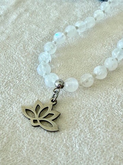 small lotus charm, detail on a Handmade Rainbow Moonstone mala necklace with 108 prayer beads, 6 mm natural gemstone beads, Aqua Aura Quartz meru, stainless steel details.
