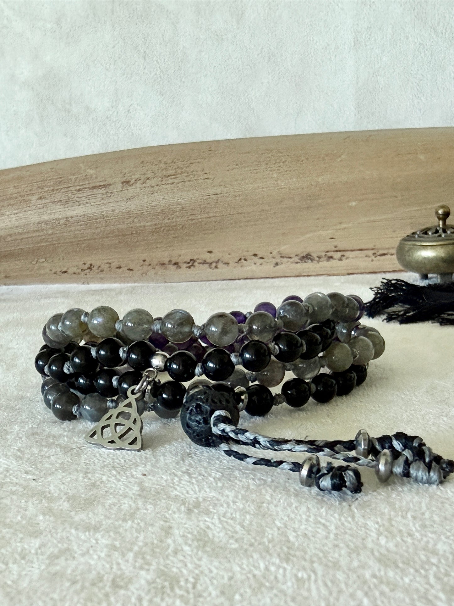 Shadow Work Mini Mala in a styled flat lay with driftwood and brass incense burner, highlighting the lava stone meru and tassel.